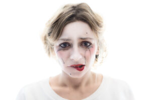 Portrait Schauspielerin mit weiß geschminktem Gesicht und von Tränen verschmiertem Mascara